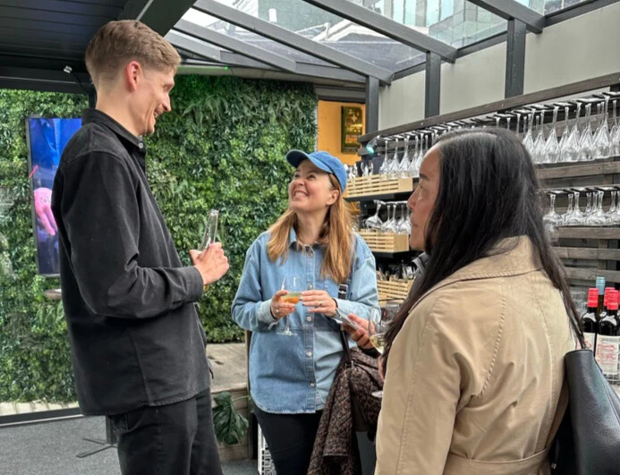 Guests mingling in front of the green wall at AI BAREN.